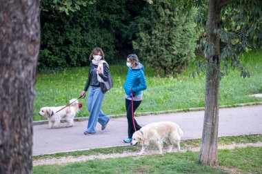 Terni, İtalya saat 10: 2020: ihtiyaçlarını gidermek için köpekleriyle birlikte parkta olan iki kadın.