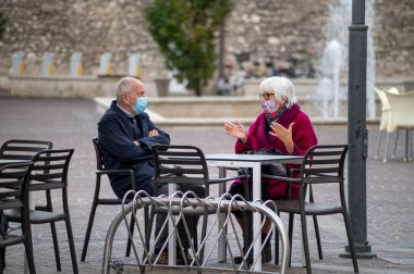 Terni, İtalya 13 Ekim 2020: Kafenin dışında oturmuş kahvaltı yapan tıbbi maskeli adam ve kadın