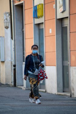 Terni, İtalya 13 Ekim 2020, şehirde yürüyen tıbbi maskeli, güneşli bir kadın.