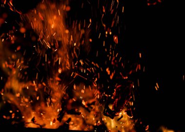 Siyah arkaplanda kıvılcımlar saçan bir ateş alevi