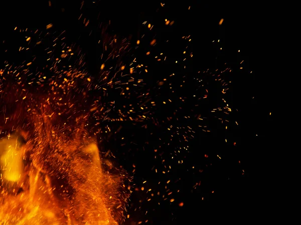 Siyah arkaplanda kıvılcımlar saçan bir ateş alevi
