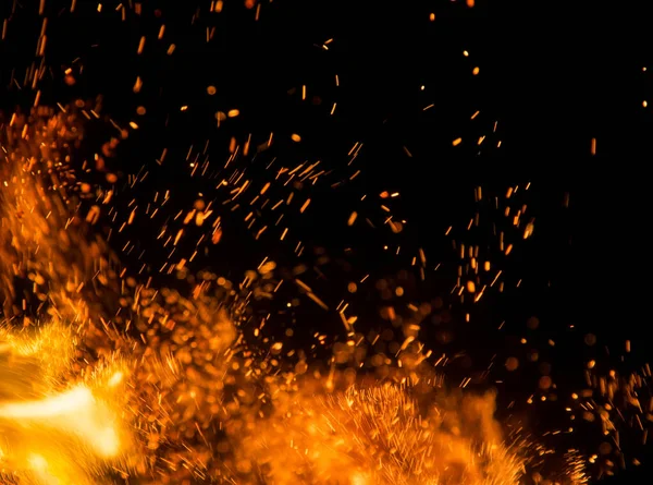 Siyah arkaplanda kıvılcımlar saçan bir ateş alevi
