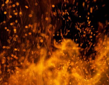 Siyah arkaplanda kıvılcımlar saçan bir ateş alevi