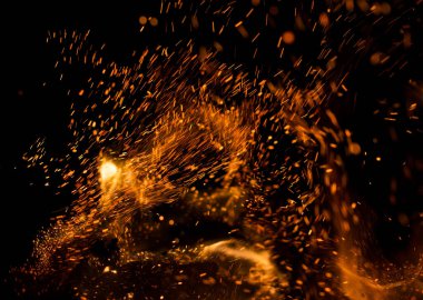 Siyah arkaplanda kıvılcımlar saçan bir ateş alevi