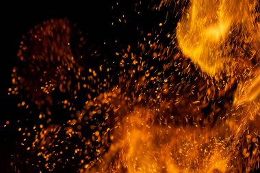 Siyah arkaplanda kıvılcımlar saçan bir ateş alevi