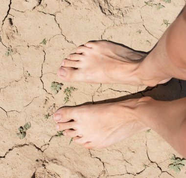 Ayaklar kuru zeminde çatlaklarla