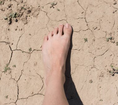 Ayaklar kuru zeminde çatlaklarla