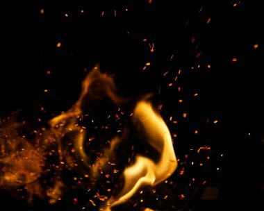 Siyah arkaplanda kıvılcımlar saçan ateş alevleri