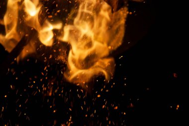 Siyah arkaplanda kıvılcımlar saçan ateş alevleri