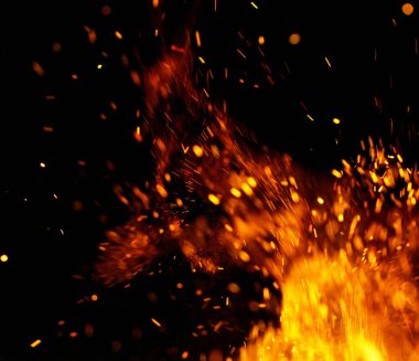 Siyah arkaplanda kıvılcımlar saçan bir ateş alevi