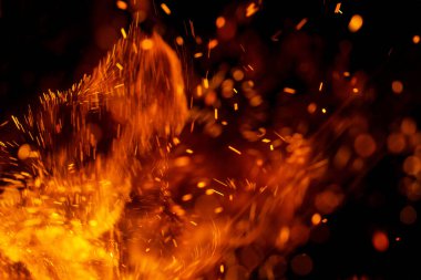 Siyah arkaplanda kıvılcımlar saçan bir ateş alevi