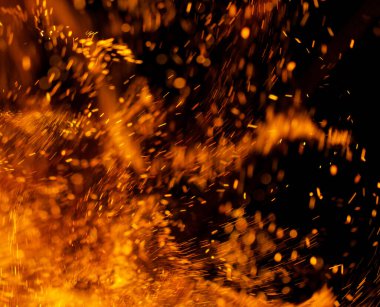 Siyah arkaplanda kıvılcımlar saçan bir ateş alevi