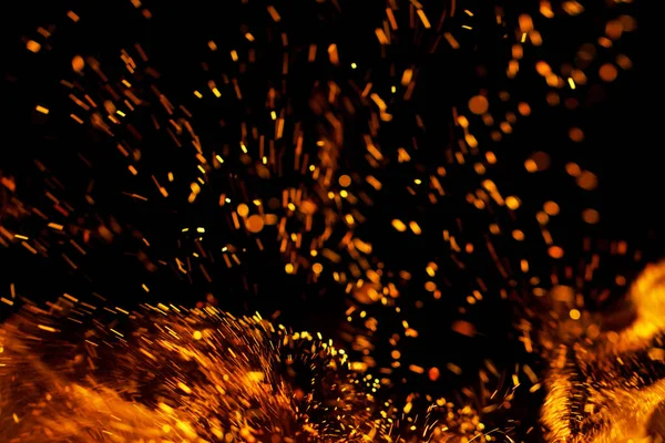 Siyah arkaplanda kıvılcımlar saçan bir ateş alevi