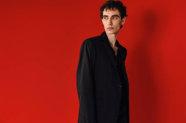 Şık bir adam zarif bir şekilde poz verir. Kırmızı, cesur bir zemine karşı..