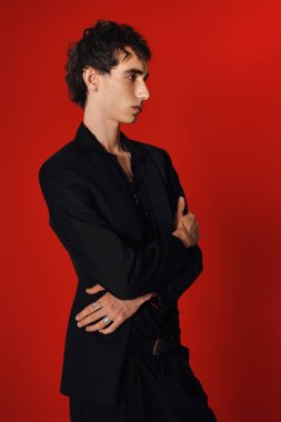 Sofistike giyinmiş yakışıklı adam, kollarını kavuşturarak rahatça poz veriyor..