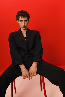 Şık bir adam zarif bir şekilde poz verir, kırmızı bir arka plana karşı..