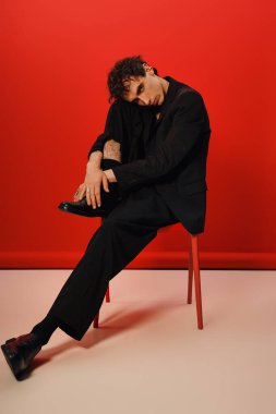 Yakışıklı bir adam sandalyede otururken zarafet ve kendine güveni somutlaştırır..