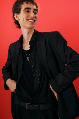 Zarif giyinmiş yakışıklı adam kendine güvenen bir şekilde gülümsüyor, karizma ve tarz yayıyor..