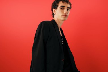 Bu şık adam dikkat çekici bir kırmızı zemine karşı özgüvenle poz veriyor..