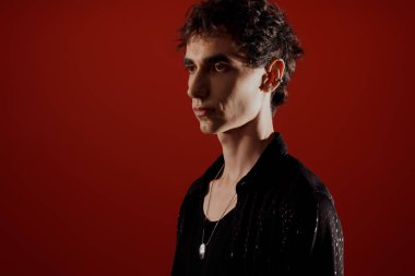 Şık bir adam cesur bir kırmızı arka plana karşı özgüvenle poz verir.