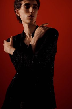 Şık bir adam kendine güvenen bir poz verir, dikkat çekici bir şekilde moda yeteneğini sergiler..