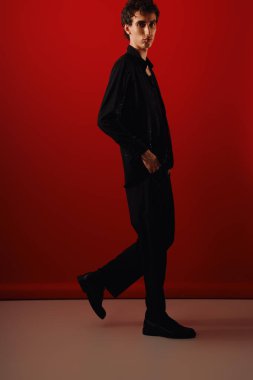 Şık bir adam, kendine güvenen kırmızı bir zemine doğru yürür, ışık saçar..