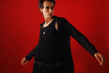 Şık bir adam canlı kırmızı bir arka plana karşı özgüven ve zarafet yayar..