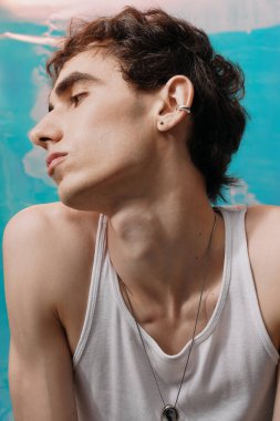 Şık bir adam, canlı bir arkaplan karşısında zarif poz verir, çağdaş moda eğilimlerini somutlaştırır..