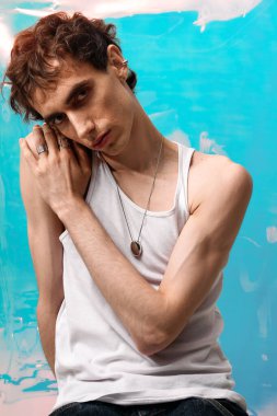 Tişörtlü yakışıklı bir adam canlı bir arkaplana karşı güvenle poz verir..