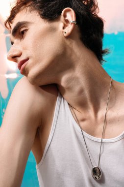 Yakışıklı bir adam zarifçe poz verir. Renkli bir arka plana karşı zarafet sergiler..