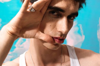 Şık giyinmiş yakışıklı bir adam kendine güvenir, rengarenk bir arka plan karşısında ışık saçar..