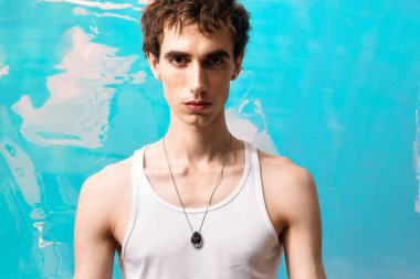 Yakışıklı adam, kendine güvenen eşsiz stilini gözler önüne seriyor, dikkat çekici mavi bir arka planla çevrili..