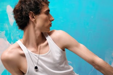 Şık bir insan şık kıyafetler içinde kendine güvenerek poz verir, sanatsal bir ortamda cazibe yayar..