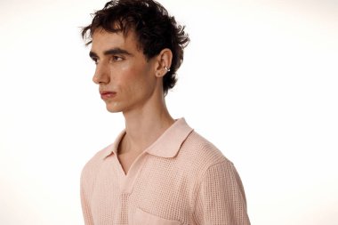 Yakışıklı adam sofistike kıyafetler giyer. Parlak, minimalist bir ortamda kendine güvenir..