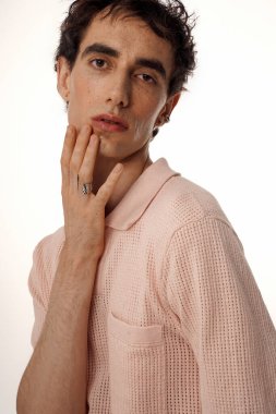 Yumuşak pembe örgü gömlekli yakışıklı bir adam zarifçe poz verir..