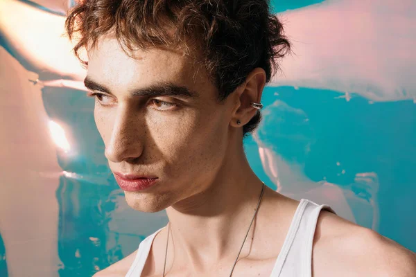 Şık giyinmiş yakışıklı bir adam kendine güven ve çekicilik saçar. Renkli bir arka plana karşı..