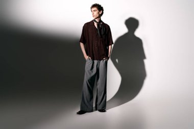 A handsome young man stands poised with hands in pockets, showcasing contemporary fashion and style.