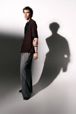 Handsome young man showcases contemporary style in a striking pose with long shadows.