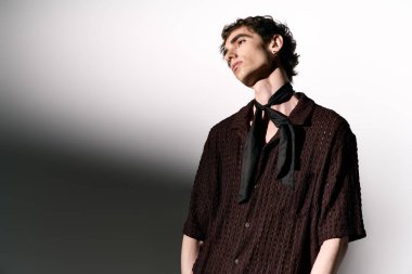 A young man stands confidently, exuding charm in trendy attire against a minimalist backdrop.