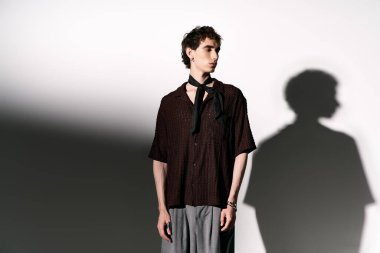 A confident young man shows off stylish attire, embodying modern fashion and charm.