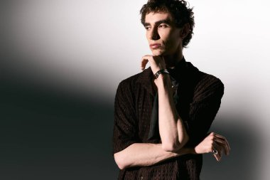 Handsome young man stands confidently in fashionable attire, radiating charisma and style.