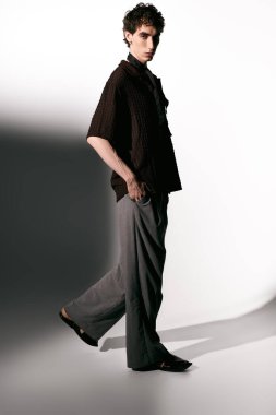 Handsome young man displays trendy attire, exuding charm and fashion elegance in a studio setting.