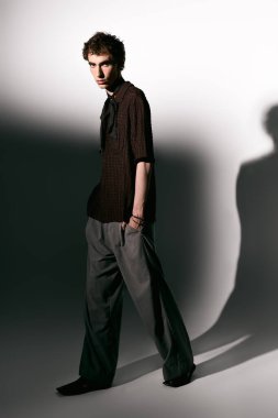 Handsome young man showcases his unique style and confidence in modern attire with dramatic shadows.
