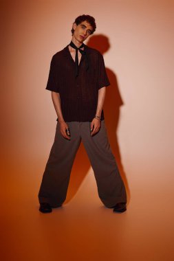 Young man showcases trendy attire with a bold pose, radiating charm and creativity.