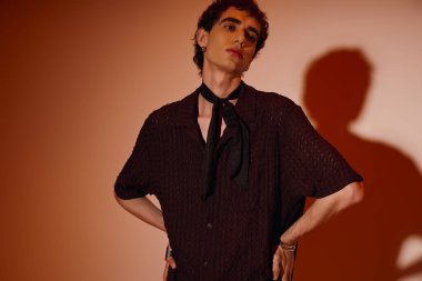 Handsome young man poses confidently, showcasing his fashion sense with striking style choices.