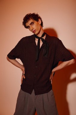 A handsome young man poses confidently in stylish attire, highlighting his fashion sense elegantly.