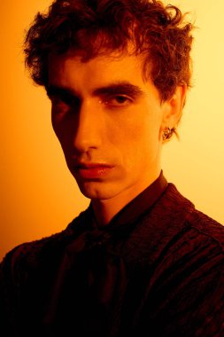 Handsome young man stands confidently in warm golden light, radiating style and charm.