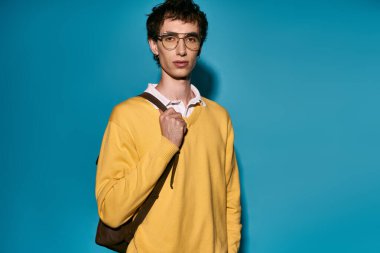 A fashionable young man stands confidently in a bright yellow sweater, exuding charm and style.