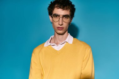 Stylish young man poses confidently in trendy glasses and a vibrant sweater.