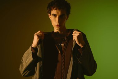 Handsome young man confidently displays fashionable attire against colorful backdrop.